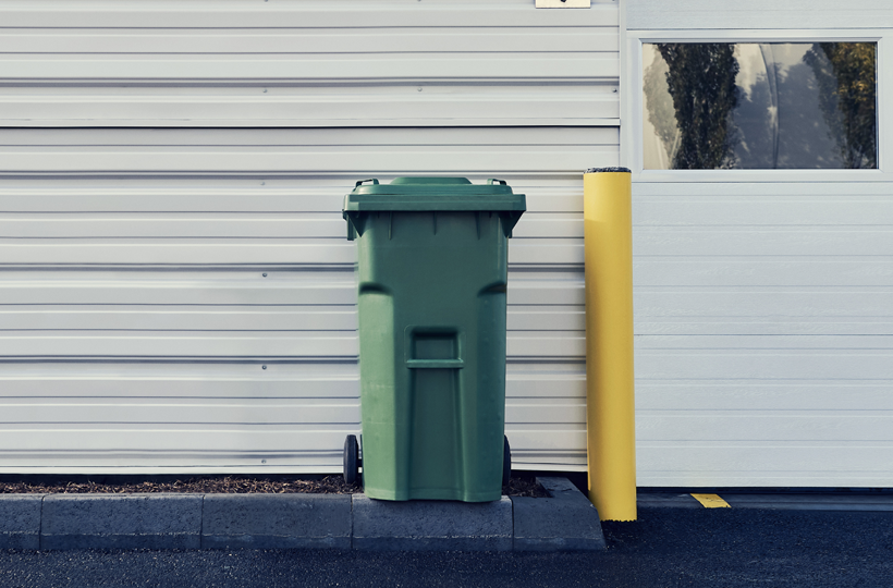 Poubelle de recyclage de papier à l'extérieur d'une installation industrielle, symbolisant la gestion des déchets et la durabilité.