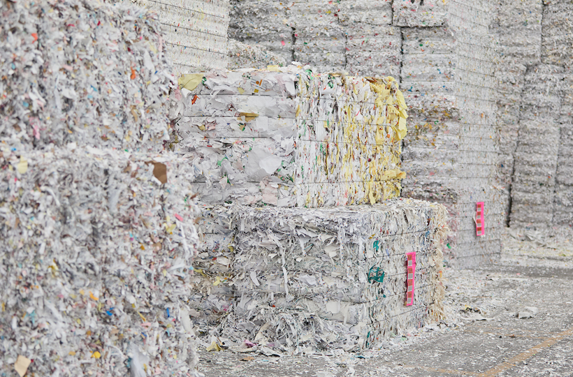De grosses balles de papier déchiqueté et compressé, prêtes à être recyclées, représentant l'économie circulaire.